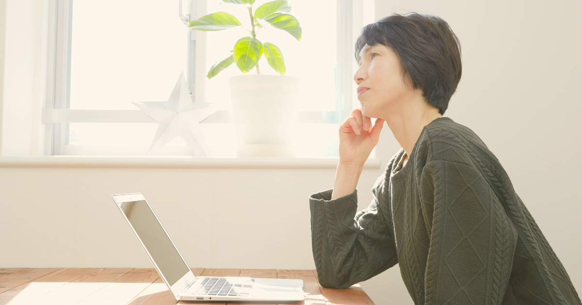 パソコンが苦手で不安を感じながらノートパソコンを前に考えている初心者の女性